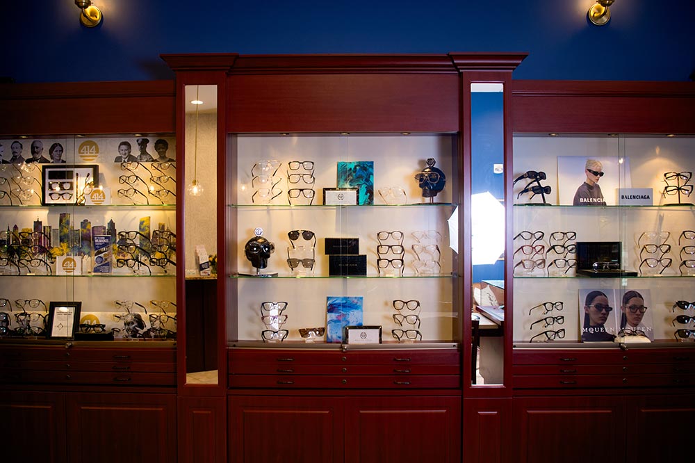 The image shows a display case filled with various pairs of eyeglasses, possibly in an optical store or similar establishment.