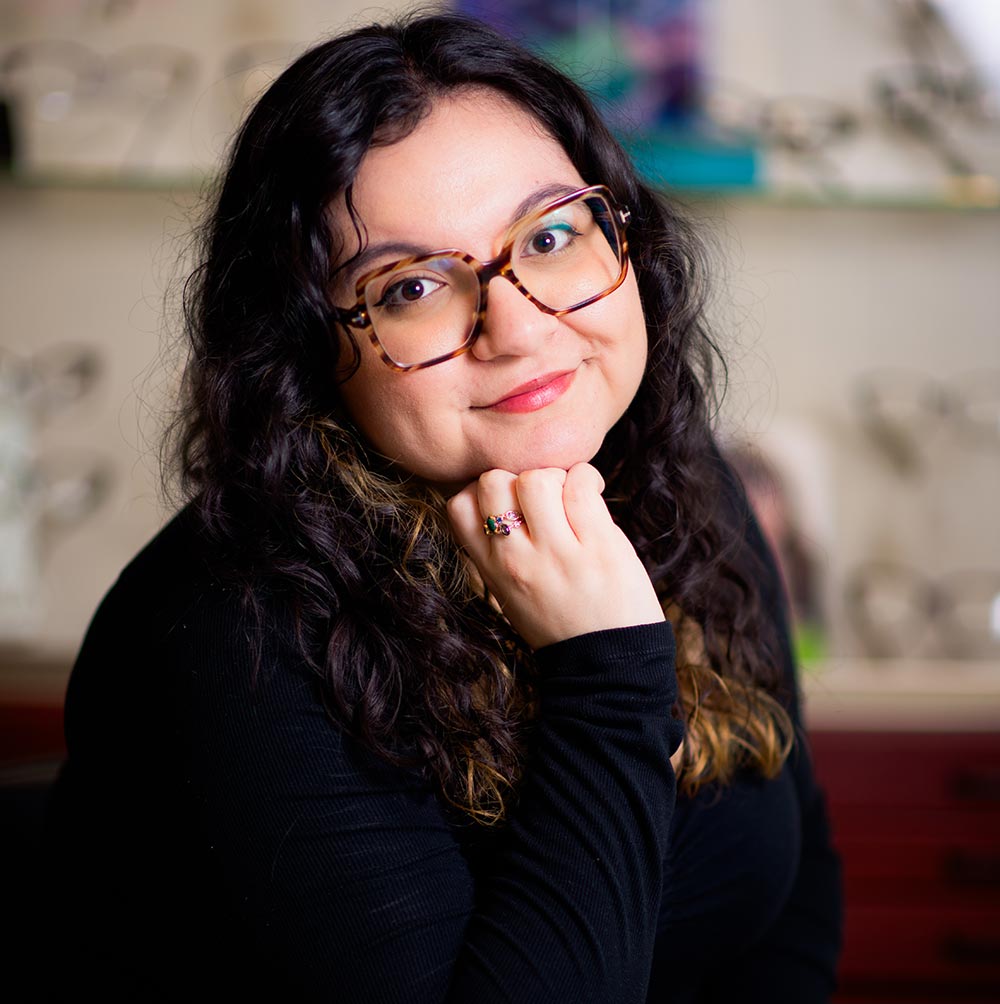 The woman in the image is wearing glasses and has her hand on her chin.