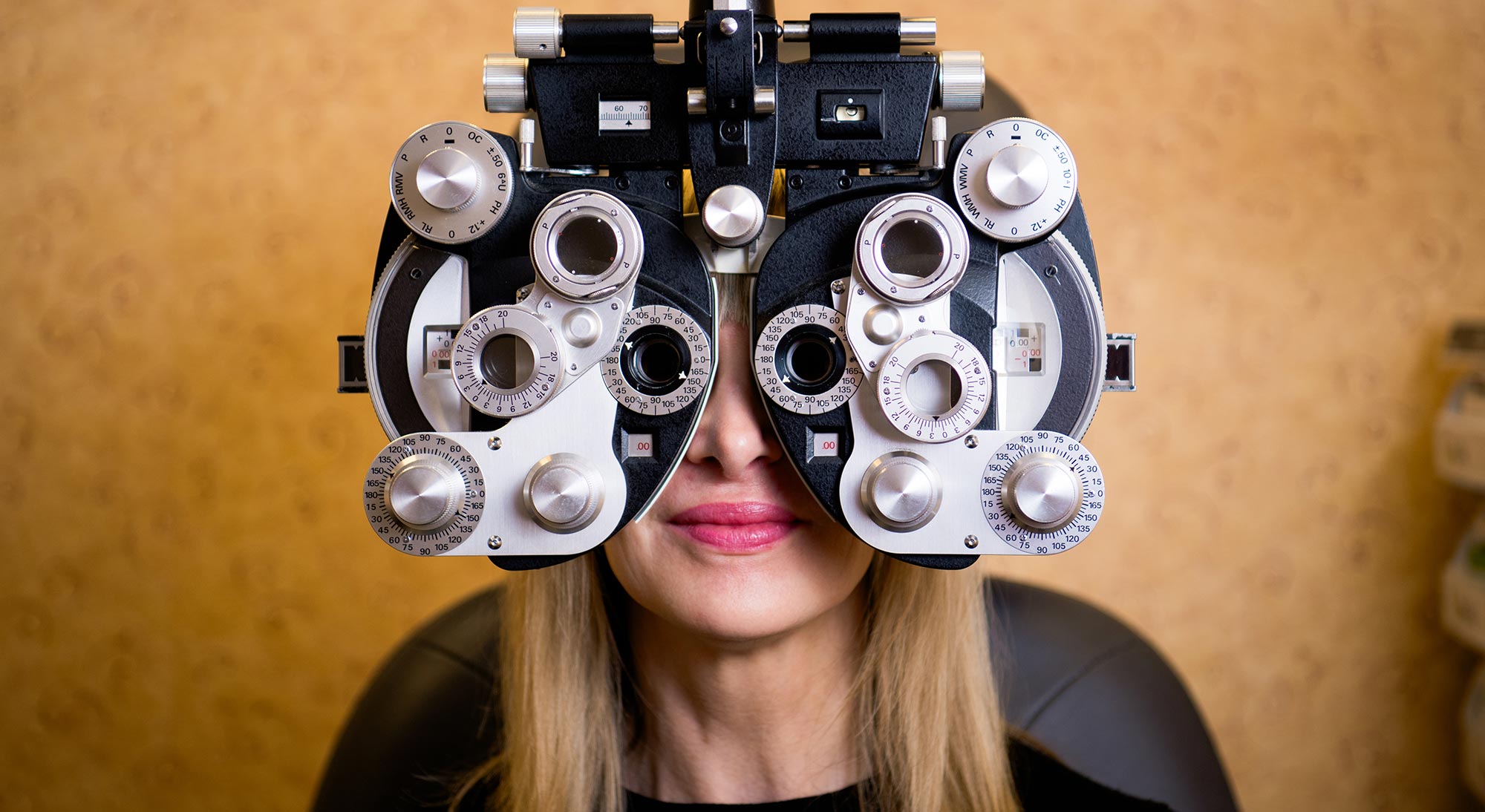 A person wearing an optical device with multiple lenses, likely a vision test machine, over their eyes.