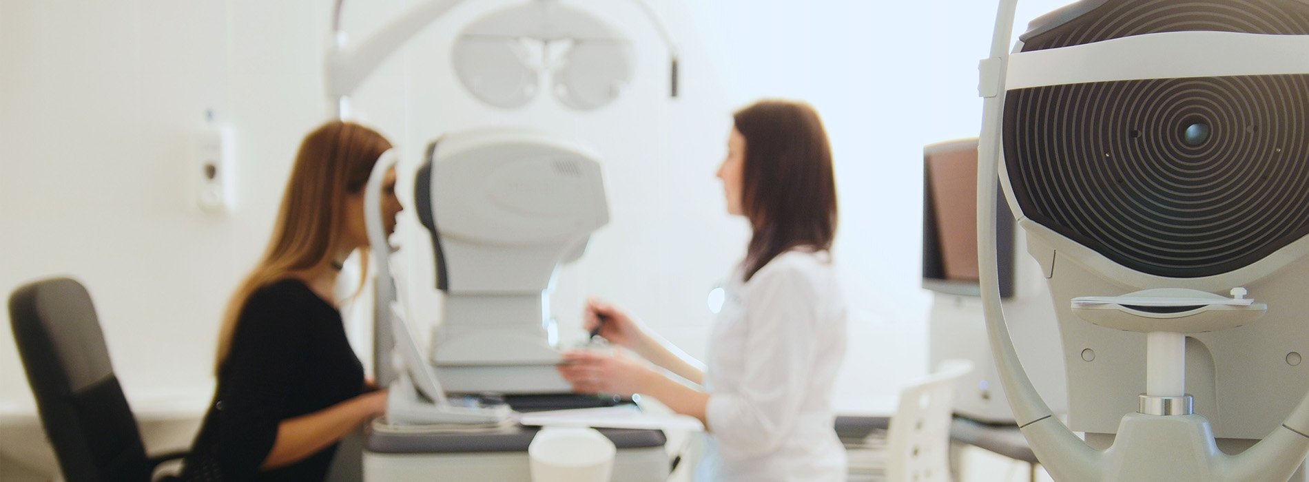 The image shows an interior setting with two individuals standing near a large piece of medical equipment, which appears to be an MRI machine, suggesting a healthcare environment.